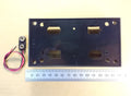 HJW Electronics product listing for A black rectangular four D battery holder with pre-drilled holes and cutouts, shown next to a small two-pin screw terminal with attached wires and a metal ruler for scale, on a beige background and PP3 connections clips.